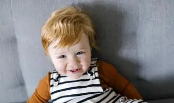 מחייך תינוק אדום שיער על הספה