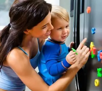 冷蔵庫に磁石を持った幼児と母親