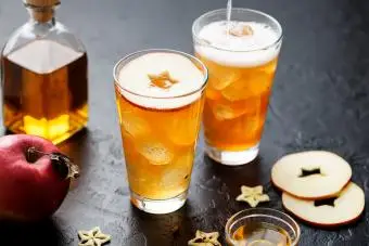 Cocktail de bière au gingembre et de whisky au miel avec des glaçons et des tranches de pomme rouge.