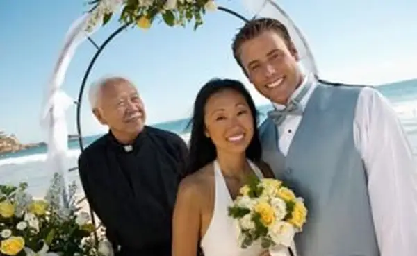 アーチ道の下で司祭と新郎新婦とのハワイビーチウェディング