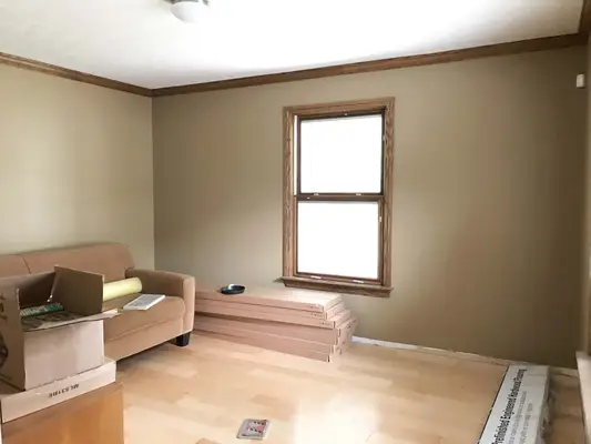 living room with a brown couch, hardwood floors, boxes, and blank walls