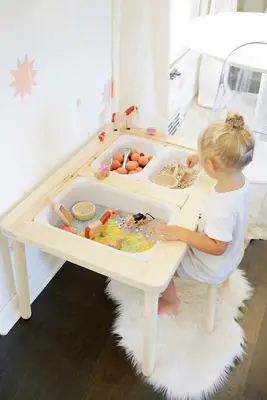 blonde little girl playing at a sensory bin table