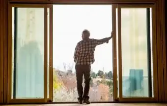 Starší muž naklonený vo dverách