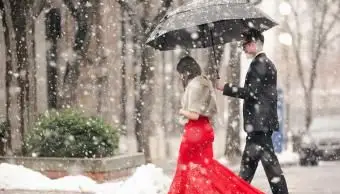 Žena v dlhých červených šatách prechádzajúca cez ulicu