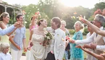 Hostia hádžu okvetné lístky ruží novomanželskému páru