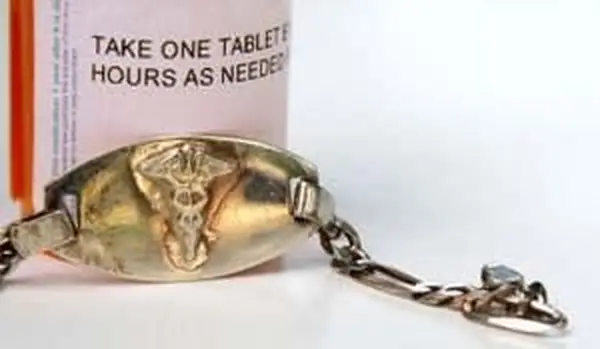 Pulseira de alerta médico ao lado de um frasco de remédio