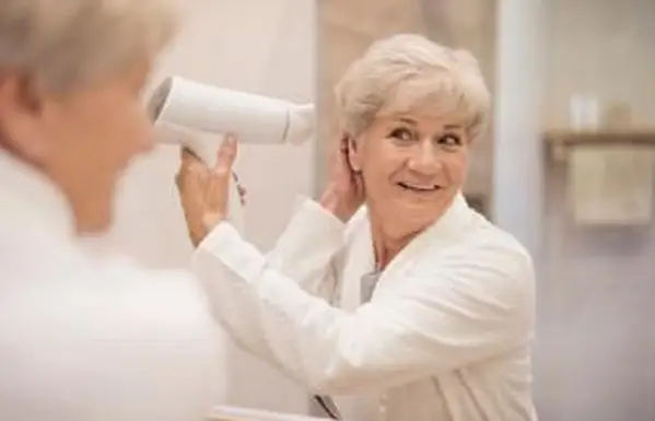 אישה בכירה מייבשת שיער