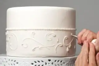 Décorations de tuyauterie sur un gâteau de mariage recouvert de fondant
