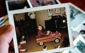 Mão segura uma fotografia vintage de um menino no carro de pedais