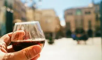 Mano sosteniendo una copa de coñac en el bar de la terraza en un día soleado