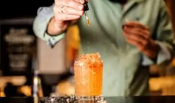O barman adiciona amargo ao coquetel de verão