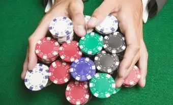 게임 테이블에 걸쳐 포커 칩의 큰 스택을 밀고 남자