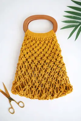 yellow macrame handbag with gold scissors next to it