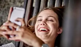 携帯電話を使用してベンチに横たわっている女性