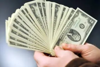 Mężczyzna trzymający dwa banknoty dolarowe