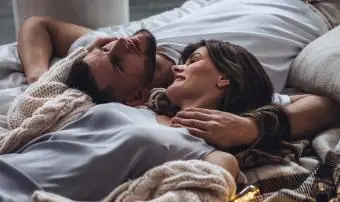 Milující mladý usměvavý pár v posteli