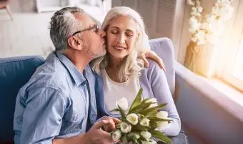 Starší muž a žena s květinami, líbání