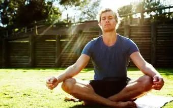 Mladý muž medituje vonku