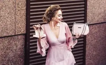 לובשת שמלה ורודה המחזיקה נעליים ורודות