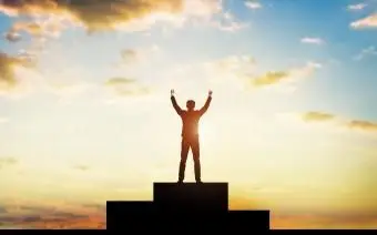 Sylwetka człowieka z podniesionymi rękami Stojący zwycięzcy Podium na tle nieba