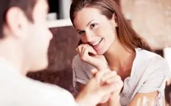 Kobieta trzymająca się za ręce z datą siedzącą przy stole