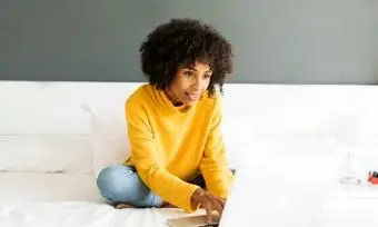 femme assise sur le lit à l'aide d'un ordinateur portable