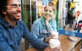 Usmievavá mladá žena v kaviarni pri pohľade na mladého muža