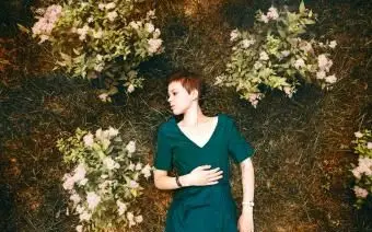 Femme portant dans l'herbe près des fleurs