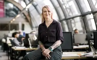 Un portrait d'un chef d'équipe élégant s'appuyant sur un bureau d'ordinateur au bureau