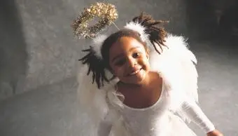 dívka s úsměvem v kostýmu anděla