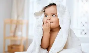 תינוקת מקסימה מכוסה במגבת לאחר אמבטיה