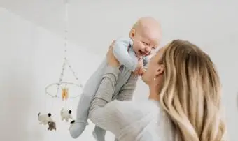 Matka hází chlapečka do vzduchu v ložnici