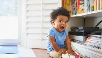 Překvapený chlapeček sedí na podlaze a hraje si s knihami