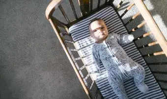 Sluneční světlo a stíny vržené na dítě ležící v dřevěné kolébce