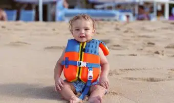 batoľa chlapec nosí záchrannú vestu na pláži