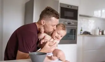 Otec políbí syna na tvář, když ho krmí obědem