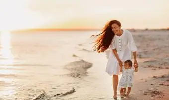 Matka a roztomilé dítě chodí naboso po bílé písečné pláži