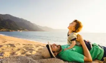 Otec a dítě na pláži při západu slunce