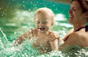 Matka striekajúcej so synčekom v bazéne