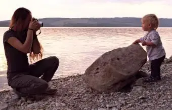 Mãe fotografando seu filho pequeno ao pôr do sol