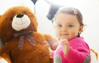 Bebé brincando com um grande ursinho de pelúcia