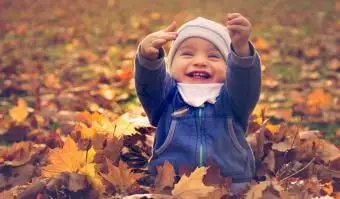 menino sentado nas folhas de outono