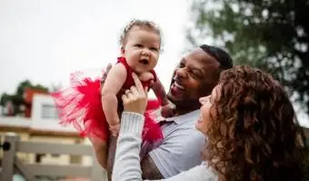 Coppia che tiene e sorride al bambino