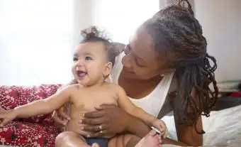 침대에 웃는 아기 딸을 들고 어머니