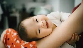 אמא מחבקת תינוק חמוד ומחייך