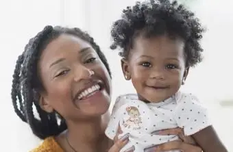 מחייכת אם שחורה מחזיקה בת תינוקת