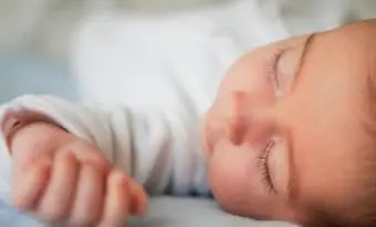 צילום מקרוב של תינוקת חמודה שישנה על המיטה