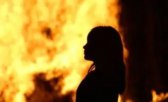 Sylwetka dziewczyny stojącej przed ogniem w nocy