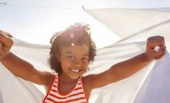 Młoda dziewczyna uśmiechnięta, trzymająca białe prześcieradło