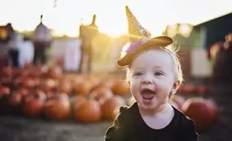 Niña gatea por el huerto de calabazas
